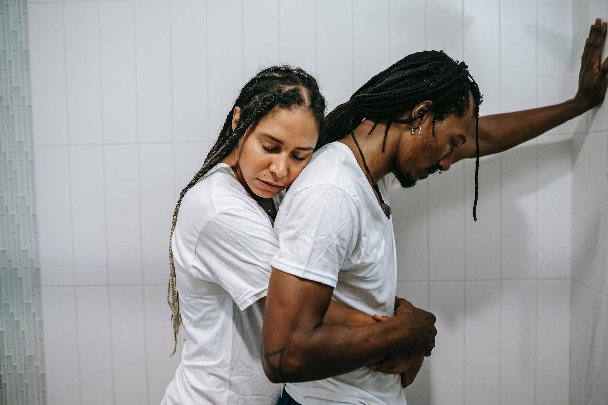 woman holds man in the shower while hugging him from behind