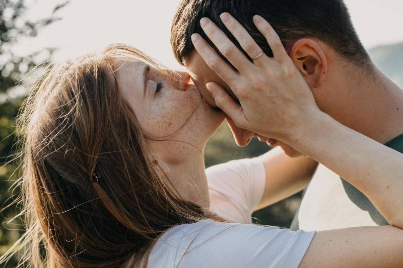 woman kisses man's forehead while holding his face