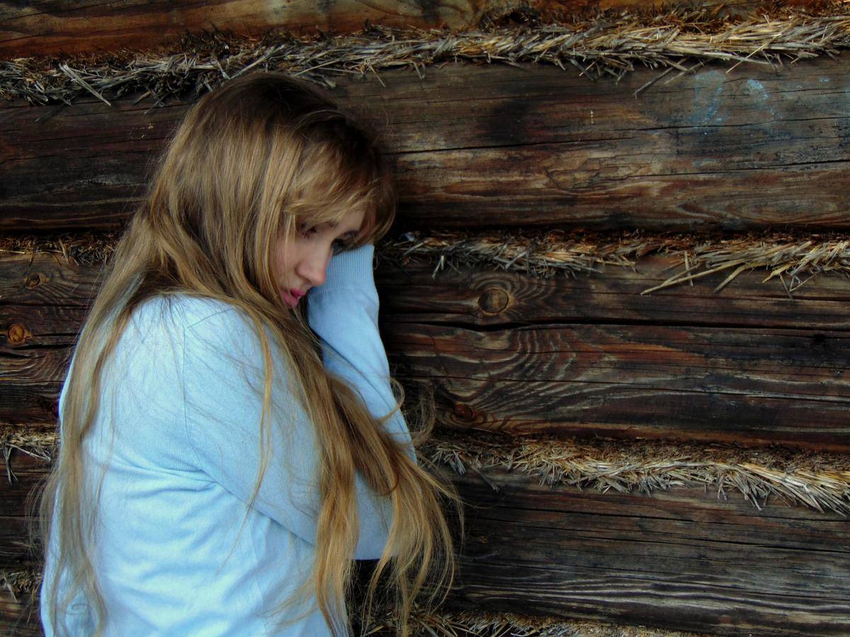 woman leaning against wood while crying
