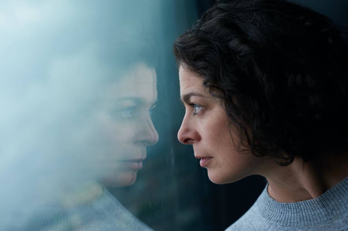 woman looking at her reflection in window