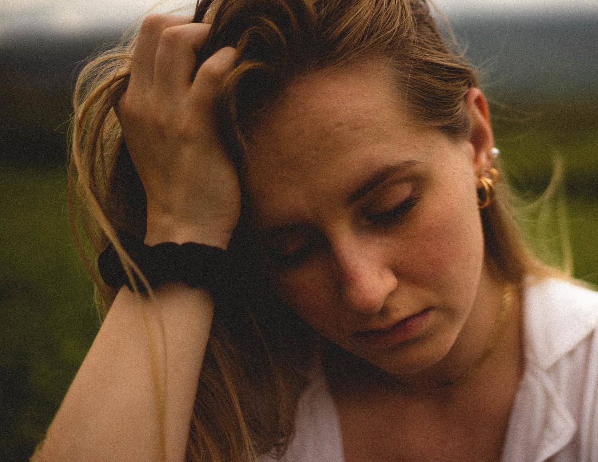 woman playing with her hair looking down in sadness