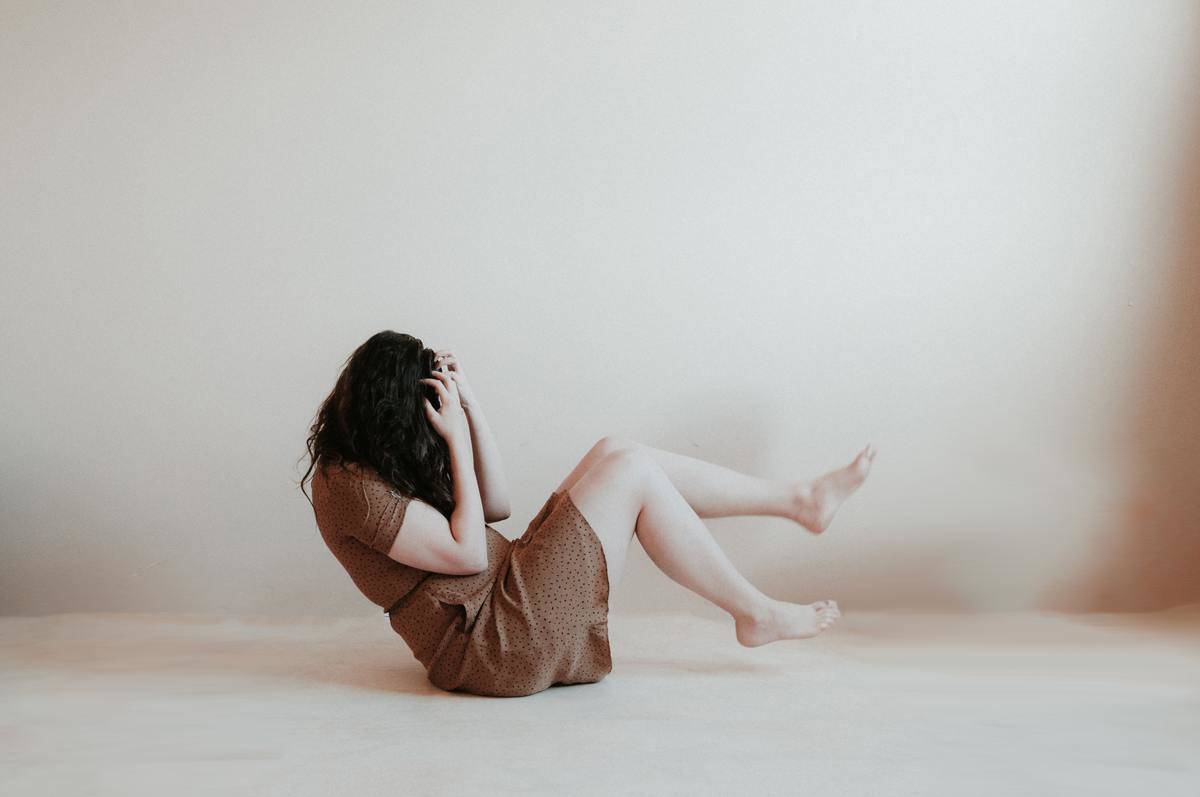 woman rocking on the floor while scratching her hair