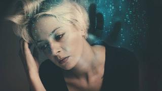 woman sitting looking off to distance with green bubbles behind her