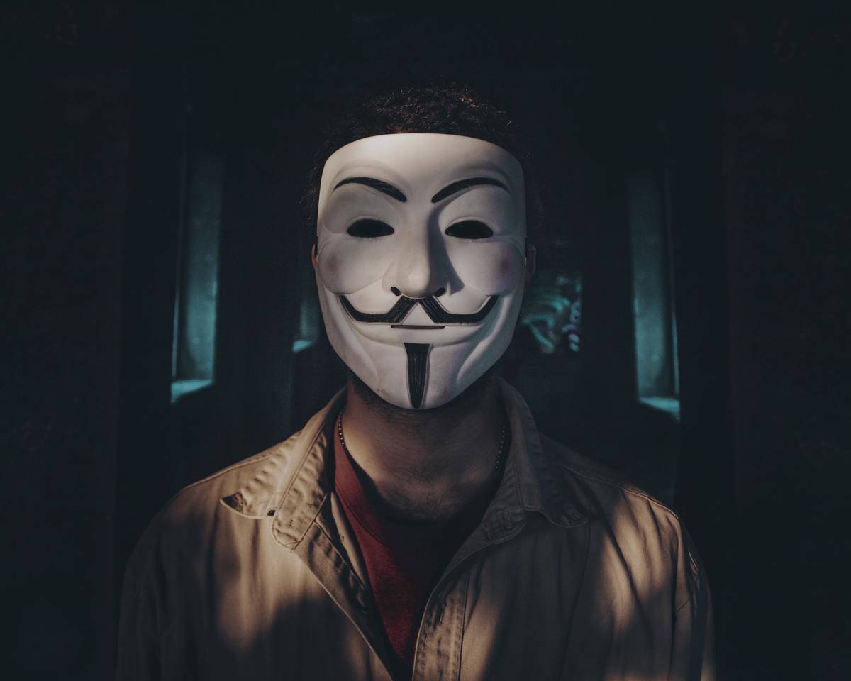 man wearing anonymous mask in dark background