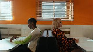 A guy and girl sitting in a restaurant with their backs facing each other.