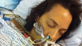 Collee in hospital bed connected to tubes unconscious