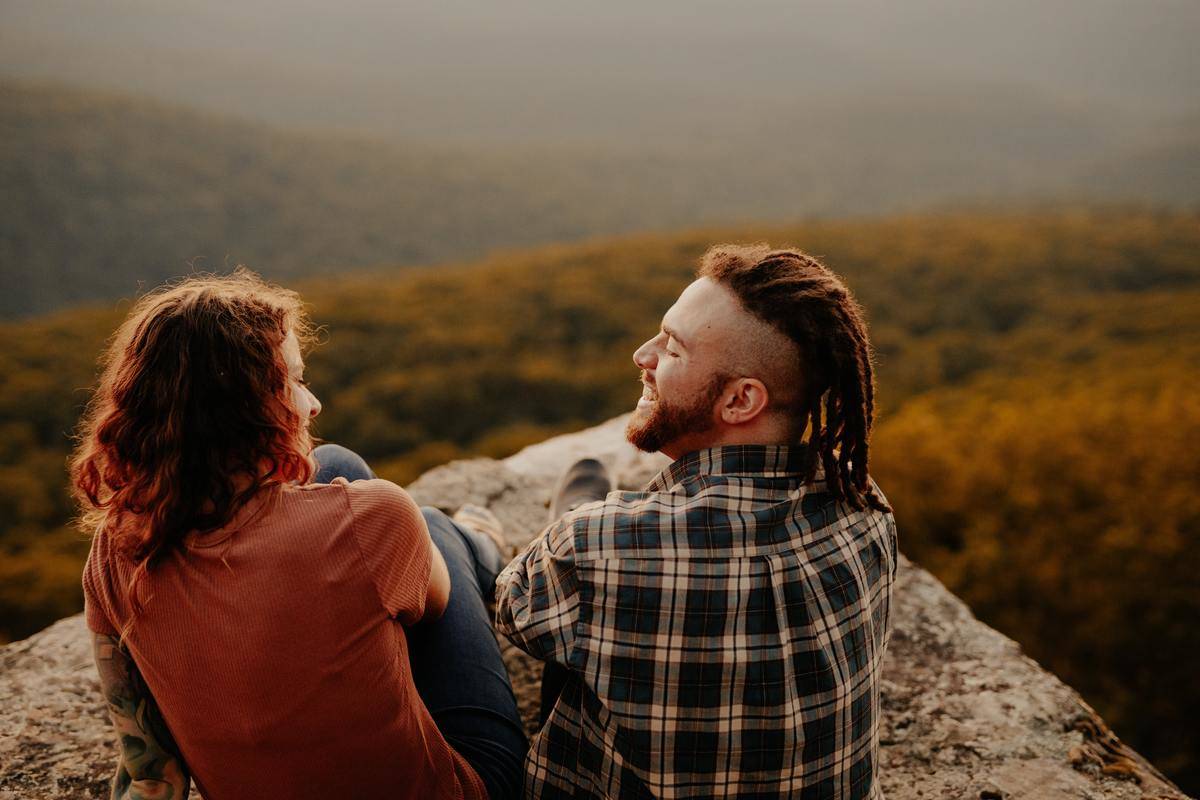 Couple sit on a cliff laughing