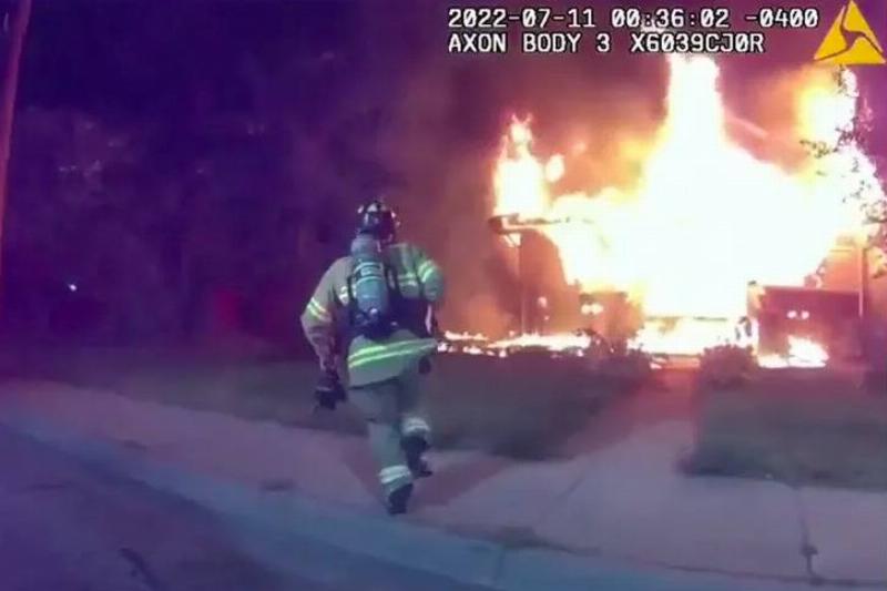 A fire fighter running towards a burning house.
