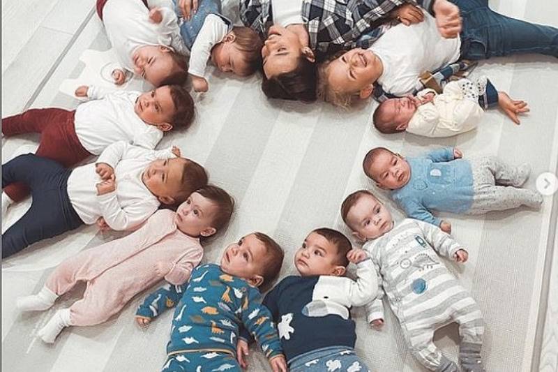 Kristina makes heart shape with babies laying on the floor