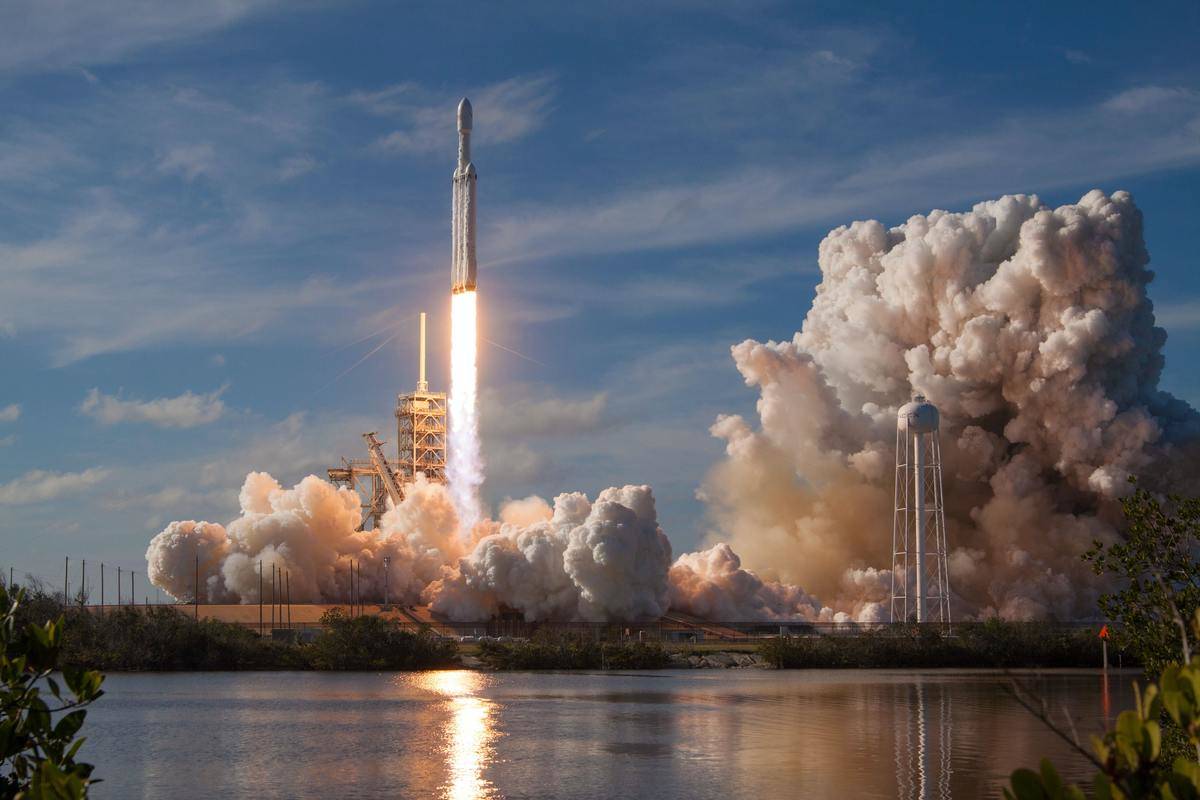 A space rocket shooting up into the air on a clear blue day.