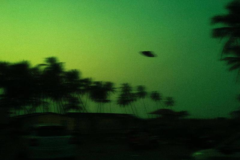 A blurry photo of a green sky with a UFO in the air.