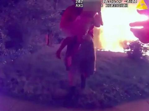 Video cam footage of a man holding a child, running out of a fire.
