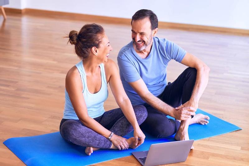 A man and woman laughing together on a yoga mat.