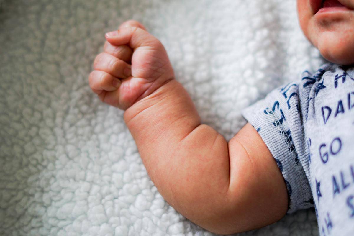 baby grips hands on blanket