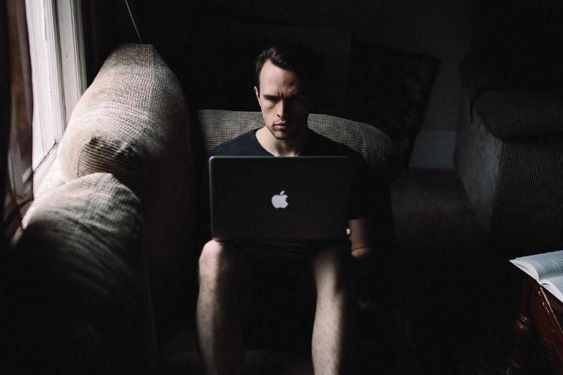 man on his laptop on couch in the dark