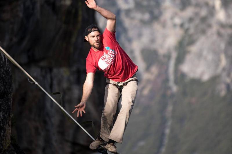 man walking tightrope between cliffs