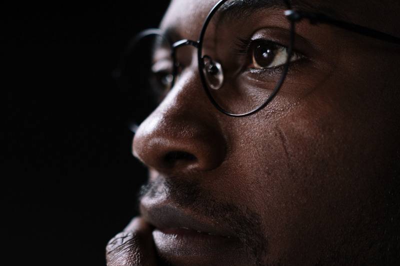 man with glasses looks deep in thought, close up of his face