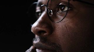 man with glasses looks deep in thought, close up of his face