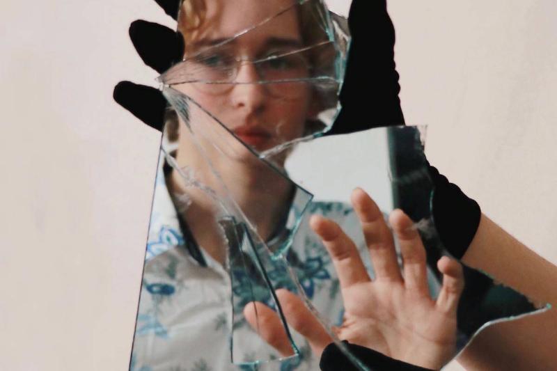 reflection of woman held by shattered mirror