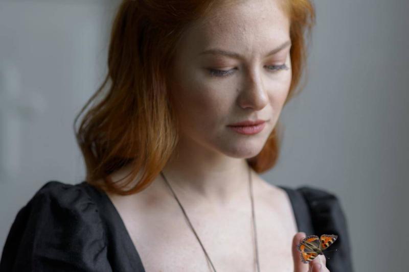 woman holding butterfly in black dress