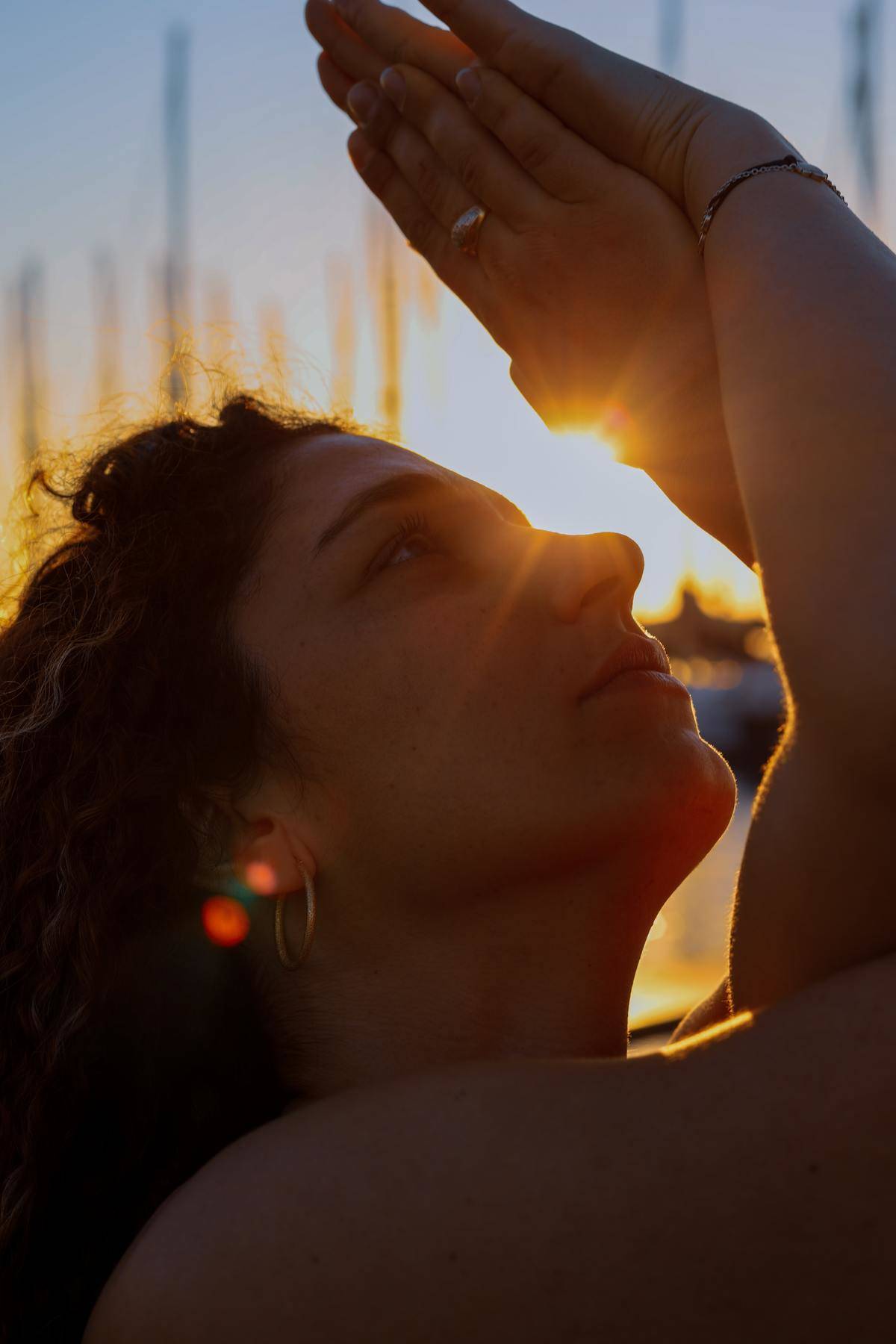 woman holding hands up to the sun and looking at them