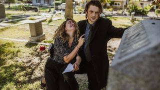 woman holding on to man crying in graveyard