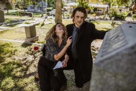 woman holding on to man crying in graveyard