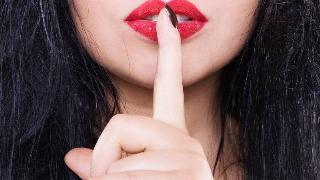 woman holds finger to her red lips in 