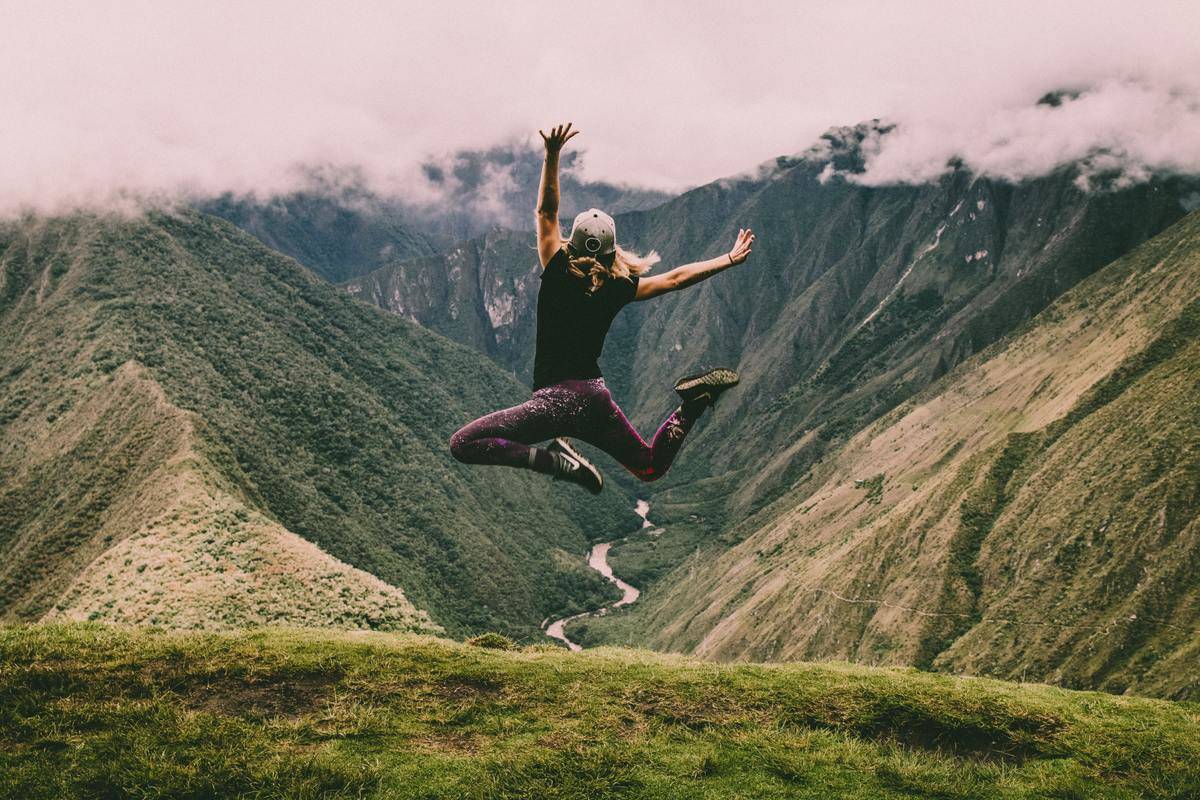 woman jumping of joy by mountains