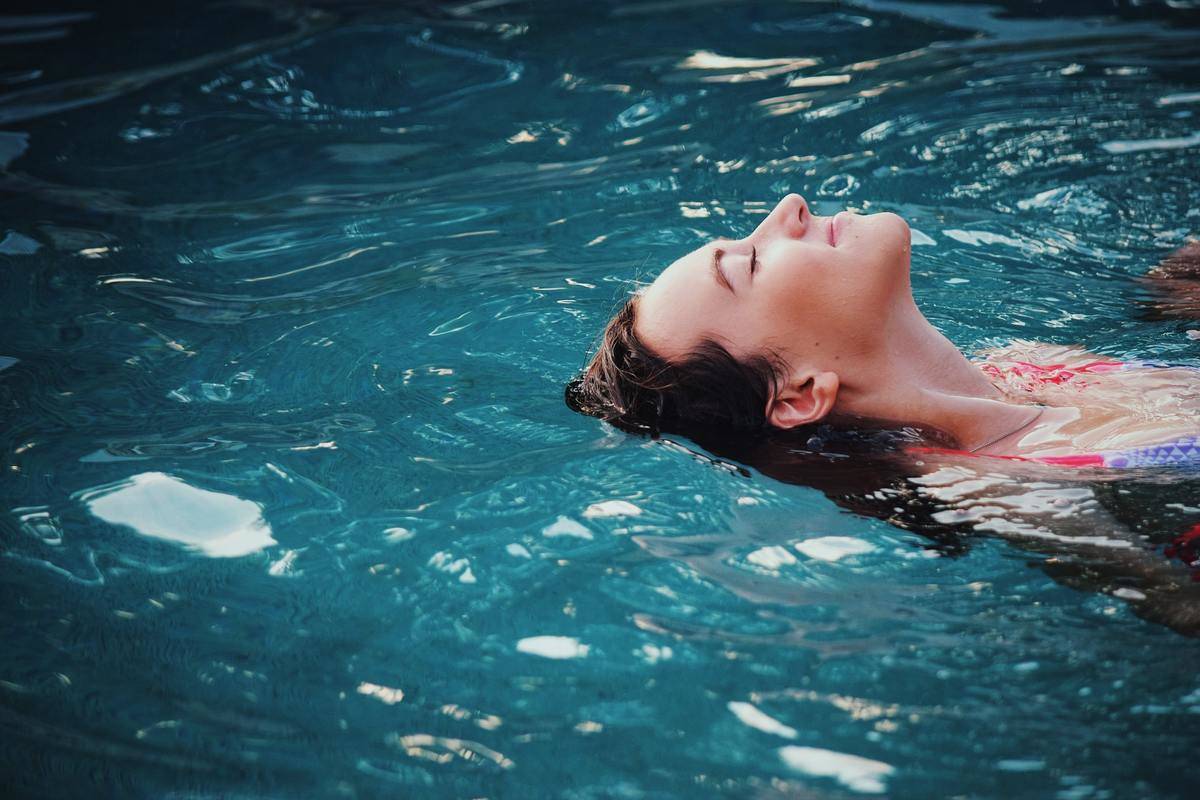 woman laying in water with her eyes closed