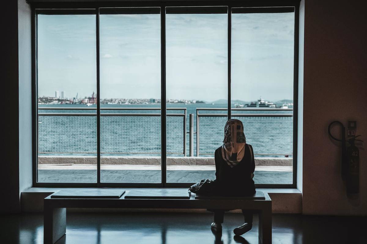 woman sitting in front of window overlooking the water