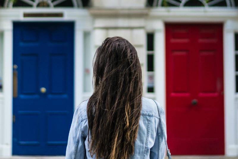woman stands in front of blue and red doors 
