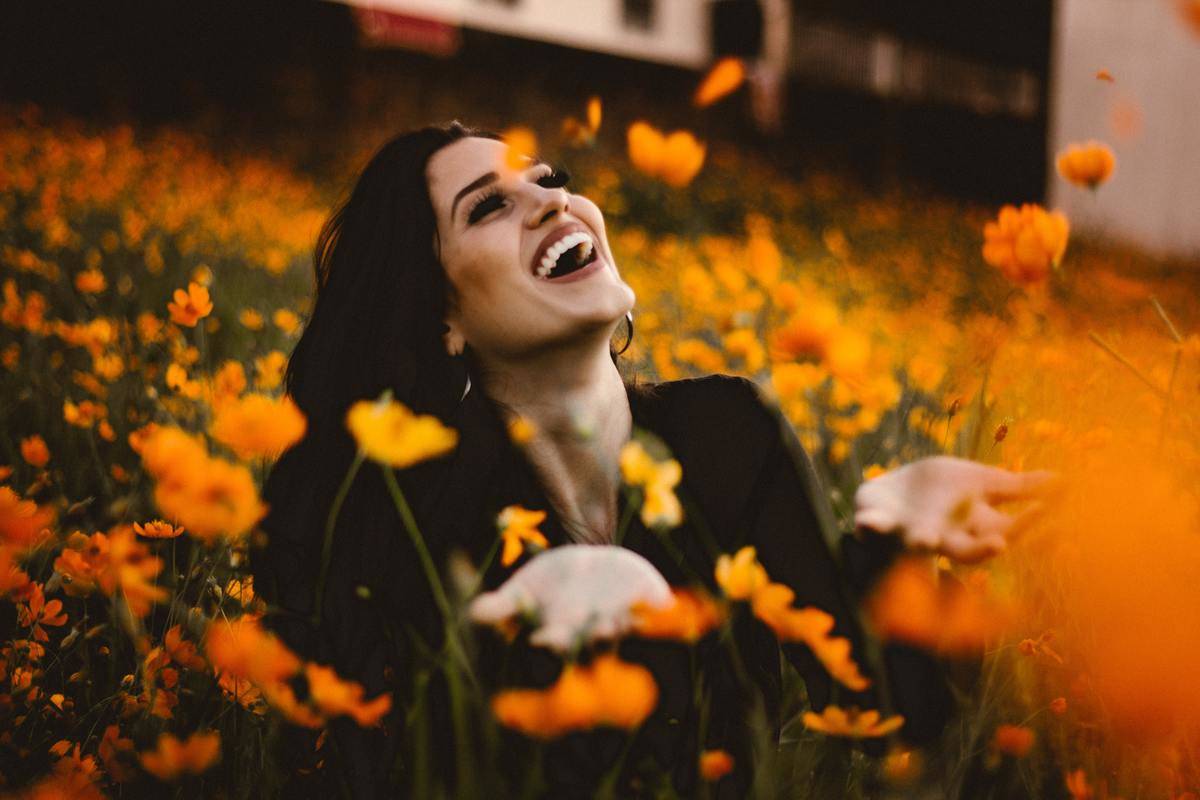woman throwing around leaves and smiles