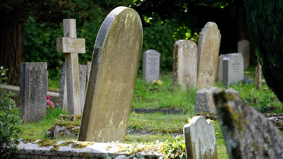 A graveyard with grass and tomb stones.