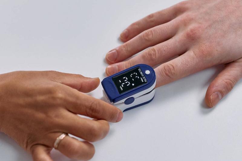 Two hands meeting at a finger heart rate monitor.