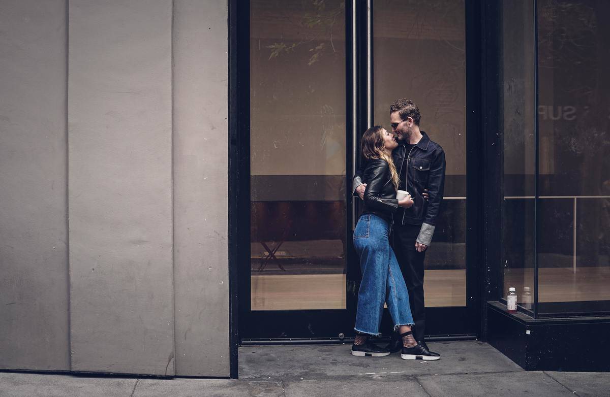 A young couple kissing outside of a building.