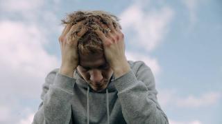 Man stressed under sky running his hands through his hair