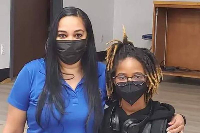 Alena and a woman in a blue shirt standing next to each other wearing face masks.