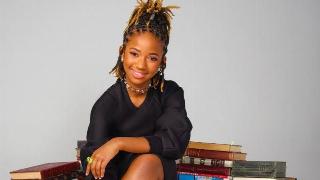 A pre-teen posing while sitting on a pile of books.