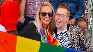 A mom and son smiling and holding a pride flag.
