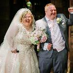 A man and woman with down syndrome leaving their wedding ceremony with smiles on their face.