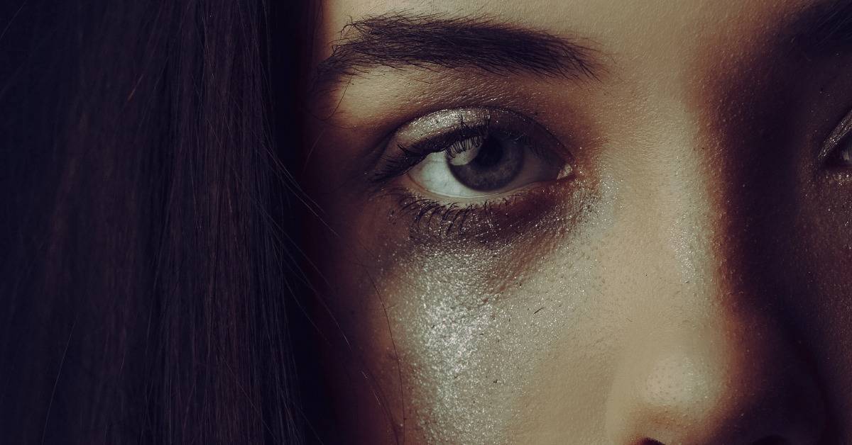 close up of sparkly tear on woman with smudged makeup