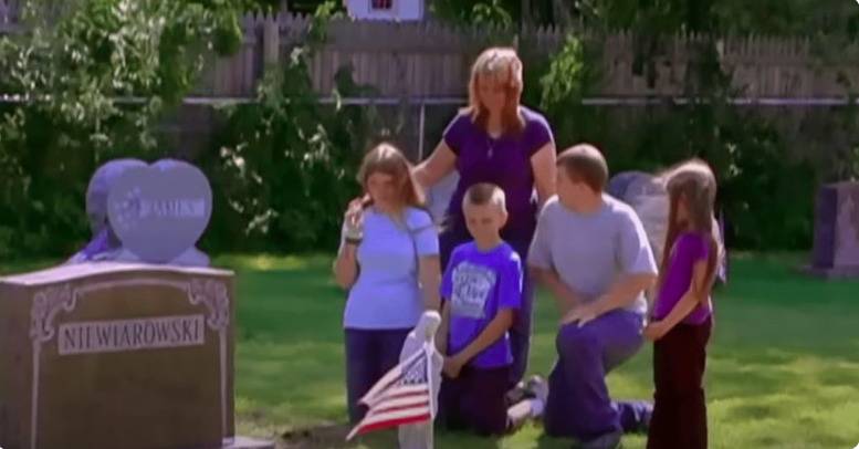 A mom and 5 children kneeling next to a grave.