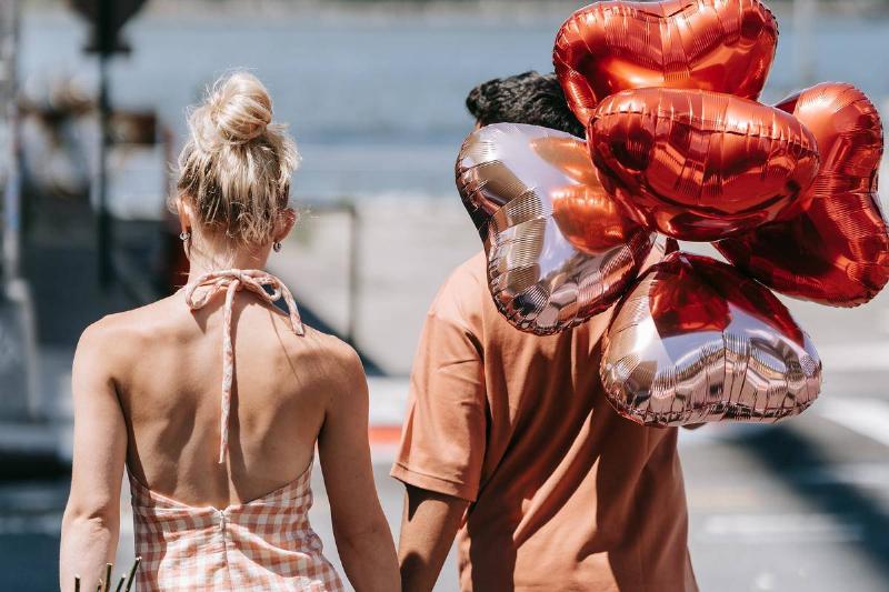 couple walking holding heart shaped balloons