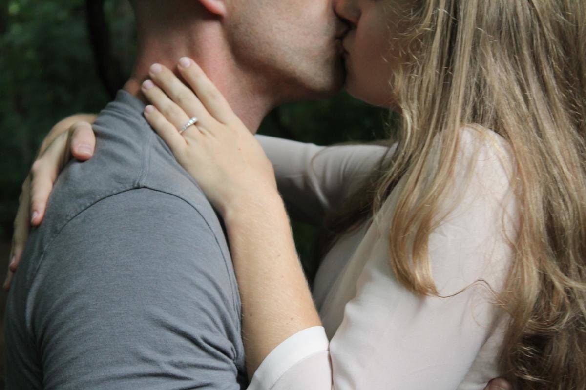 man and woman with engagement ring kiss