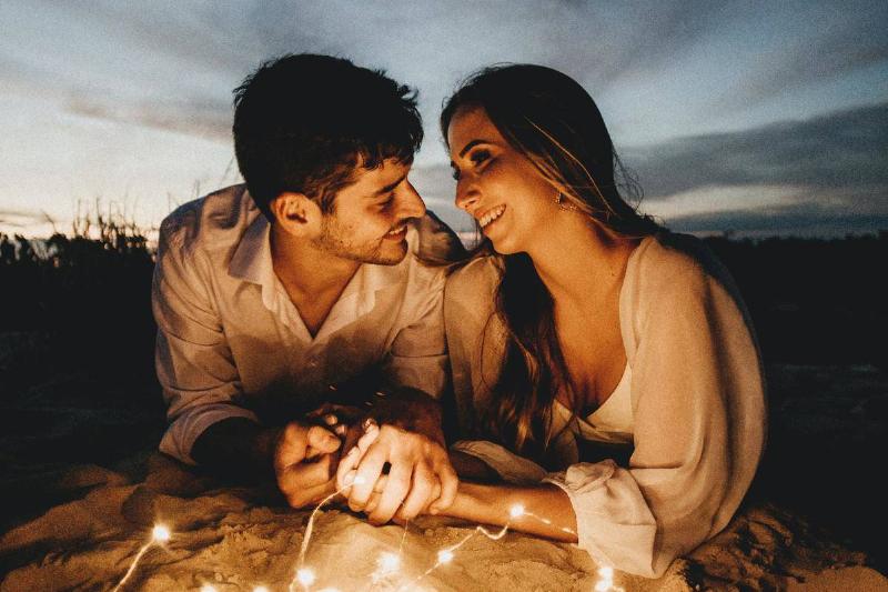 omantic-couple-holding-hands-in-evening- on blanket with string lights
