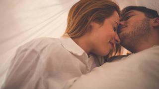 couple under the sheets smiling with eyes closed