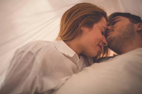 couple under the sheets smiling with eyes closed