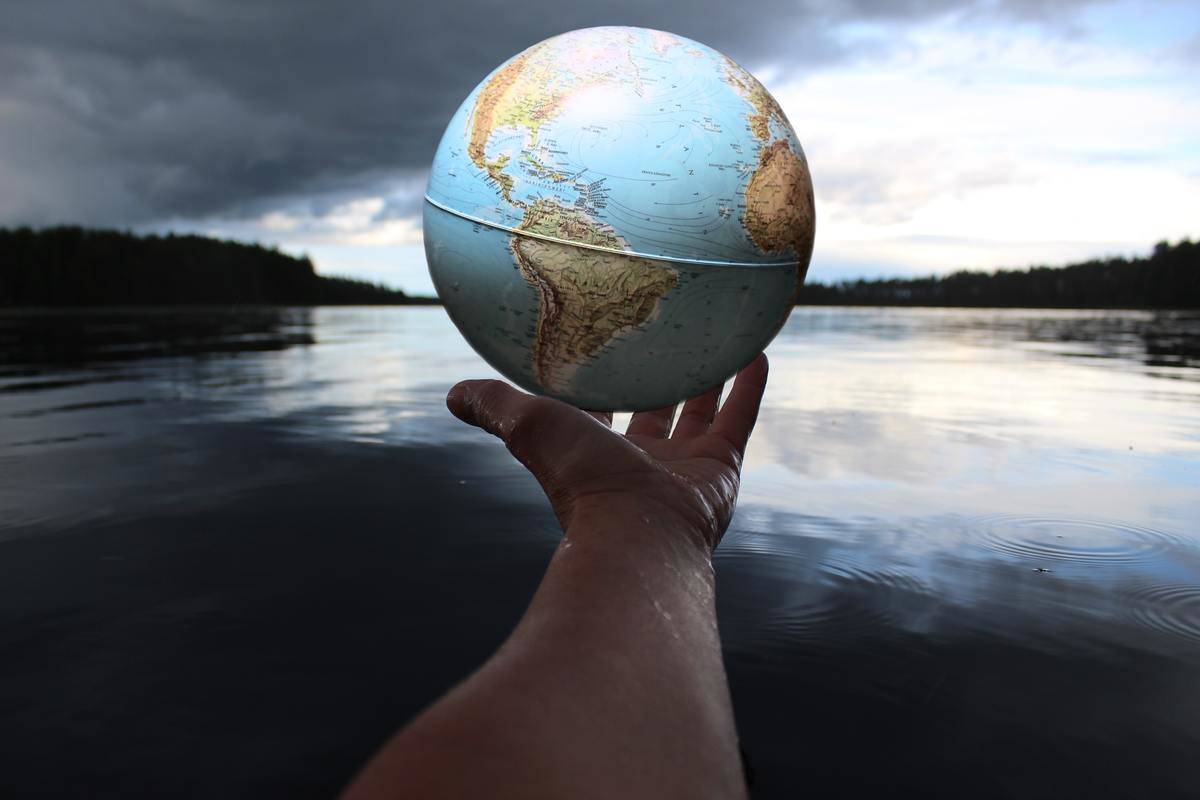 hand holding globe by the lake