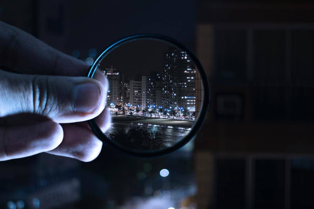person-holding-magnifying-glass-to buildings